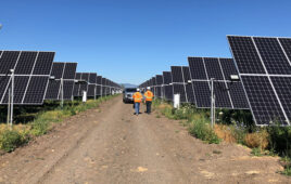 Contractors walk on an access road between rows of solar panels.